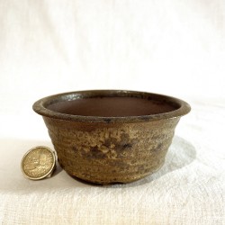 Handcrafted round bonsai pot in speckled green stoneware glaze with dark spots, horizontal texture and rustic finish