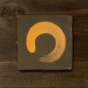 Ceramic relief featuring the golden Zen Ensō symbol on dark wood by Ismael Garcia Burillo