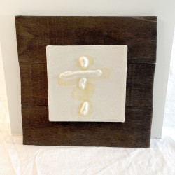 Ceramic relief featuring a vertical abstract figure suggesting a being on a dark wood panel by Ismael Garcia Burillo