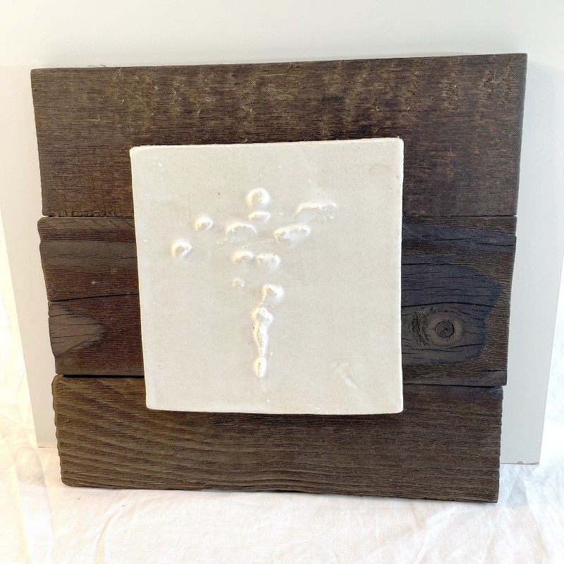Relieve cerámico blanco con formas modulares expansivas verticales sobre panel de madera oscura de Ismael García Burillo